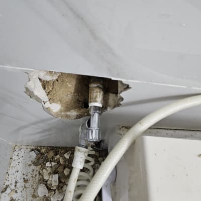 צינור מים מחובר לקיר עם חור ותשתית חשופה