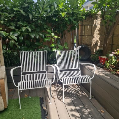 שני כיסאות מתכת לבנים על דק עץ בגינה