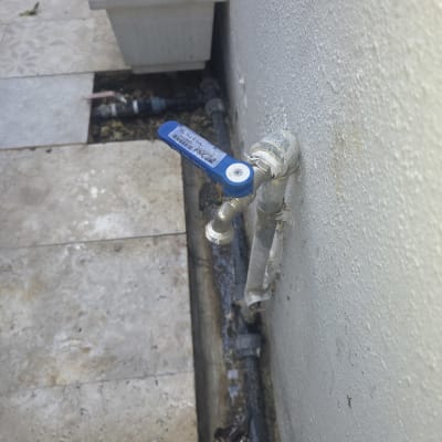 ברז מים חיצוני עם ידית כחולה על קיר