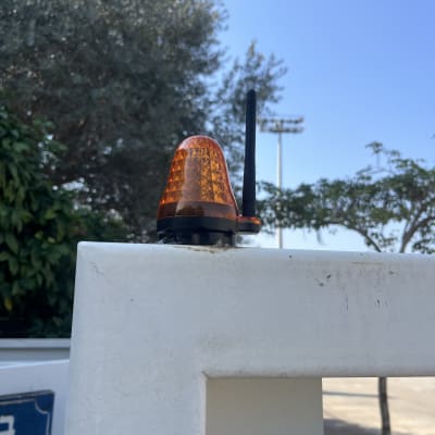 אור מהבהב כתום ואנטנה על שער חשמלי לבן