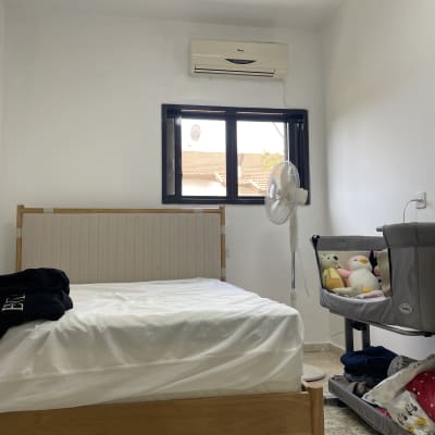 חדר שינה עם מיטה, עריסה ומזגן על הקיר