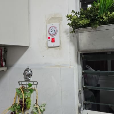 שעון טיימר חשמלי מותקן על הקיר עם נורית חיווי אדומה