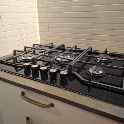 כיריים גז על משטח מטבח עם אריחי קיר לבנים