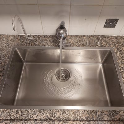 שיש גרניט אפור עם כיור נירוסטה וברז מים זורמים