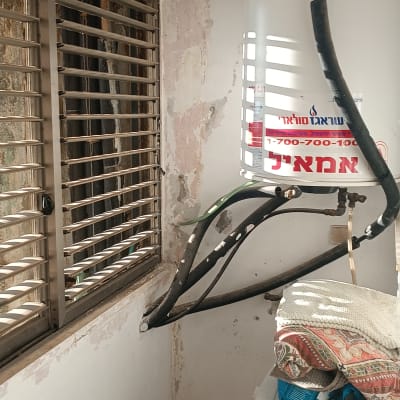 דוד שמש עם צינורות מחוברים על קיר מתקלף