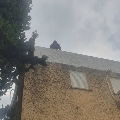 אדם על גג מבנה עם חומר איטום