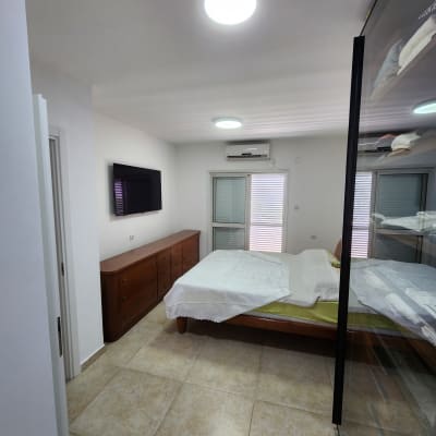 חדר שינה עם קירות צבועים בלבן ותאורה בהירה