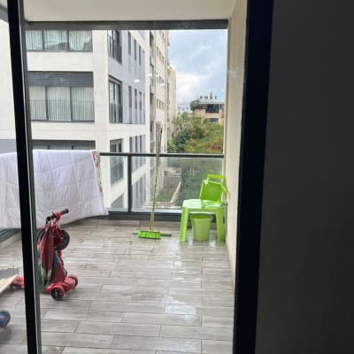 מרפסת עם דלת זכוכית, כיסאות ירוקים ומטאטא