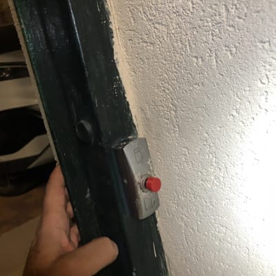 לחצן אינטרקום אדום מותקן על קיר לבן