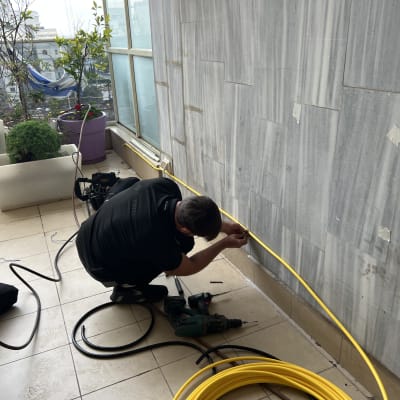 אדם מתקין צינור גז צהוב על קיר חיצוני