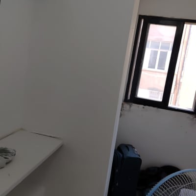 מאוורר וחלון בחדר עם קיר צבוע