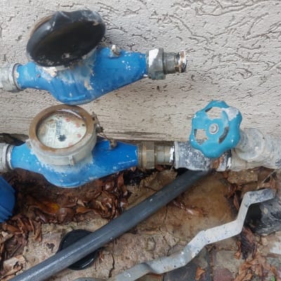 מד מים כחול עם ברז סיבובי על קיר