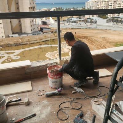 עובד מבצע עבודות שיפוץ במרפסת עם כלים וחומרים