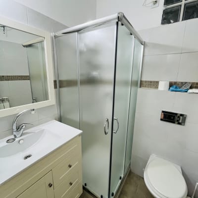 מקלחון זכוכית בחדר אמבטיה עם כיור ושירותים