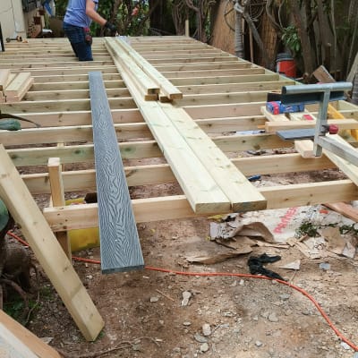 אדם עובד על מבנה עץ בגינה עם עצים מסביב