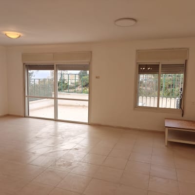 חדר ריק עם רצפת אריחים, חלונות גדולים ושולחן קטן