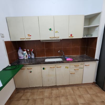 מטבח עם ארונות, כיור, חומרי ניקוי וספוג ורוד