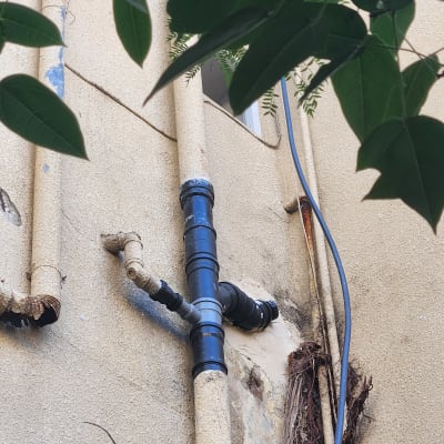 צנרת חיצונית על קיר בניין עם עלים ברקע