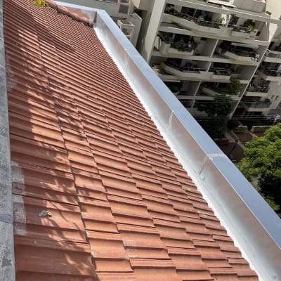 גג רעפים אדומים עם תעלה מתכתית בצד