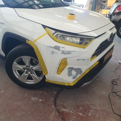 רכב בתהליך תיקון פחחות עם מסקינג טייפ וציוד עבודה