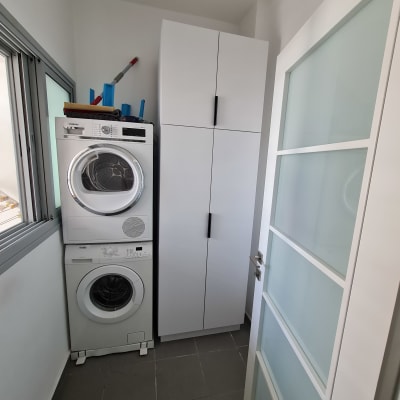 ארון לבן עם ידיות שחורות בחדר כביסה