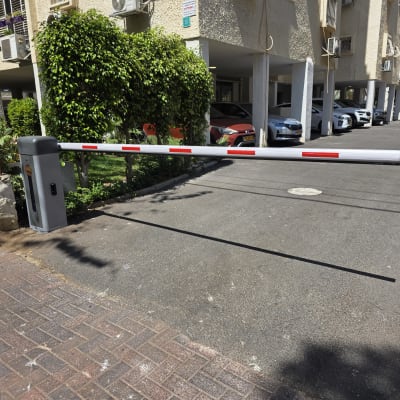 מחסום חשמלי בכניסה לחניון עם מכוניות ברקע