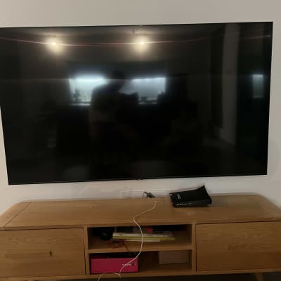 טלוויזיה תלויה על הקיר מעל שידה מעץ