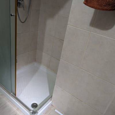 מקלחון עם אריחים וכלי ניקוי בפינה