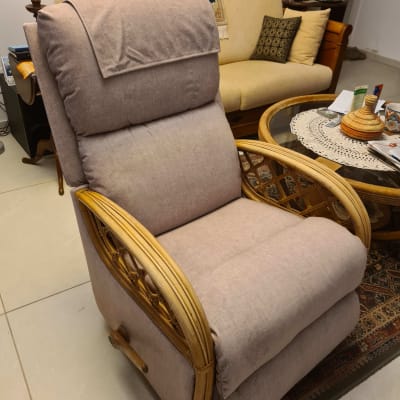 כורסה מרופדת בבד אפור עם מסגרת עץ קלוע