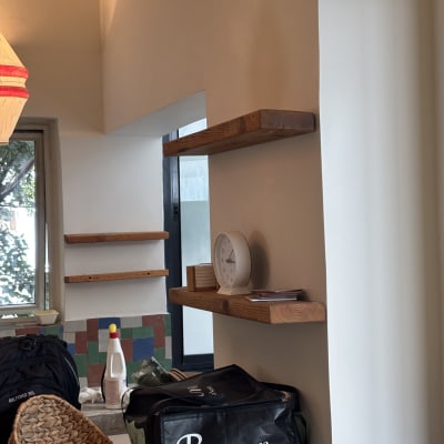 מדפים מעץ מותקנים על קיר, סלסלות קש, בקבוק חומר ניקוי