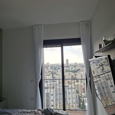 חדר שינה עם חלון גדול ונוף לעיר