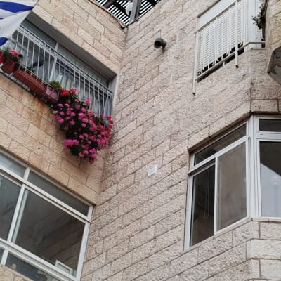 קיר אבן עם מצלמת אבטחה ומעקה מתכת