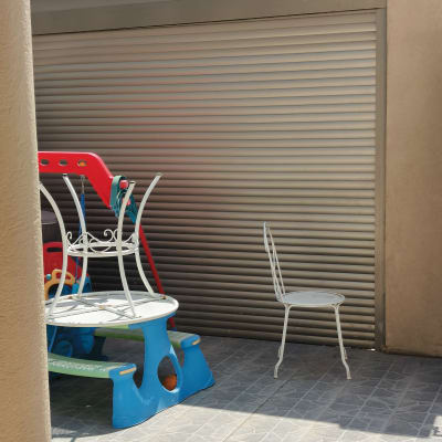 תריס מתכת סגור בחצר עם כיסא ושולחן פלסטיק