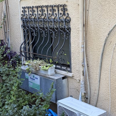 יחידת מיזוג אוויר מותקנת ליד חלון עם סורגים