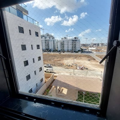 רשת יונים מותקנת על חלון עם נוף לבניינים