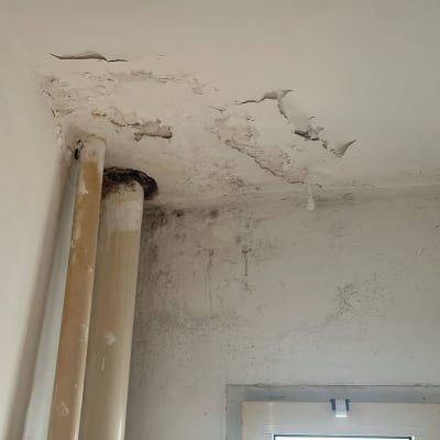 תקרה מתקלפת עם צינורות ליד חלון קטן