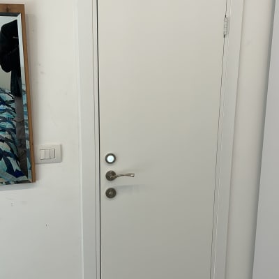 דלת לבנה עם ידית מתכת על קיר לבן