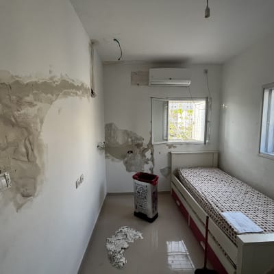 חדר עם קירות מתוקנים, מיטה וכלי עבודה לצביעה