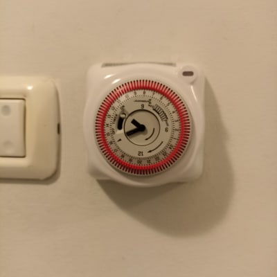 שעון טיימר חשמלי ליד מתג על קיר