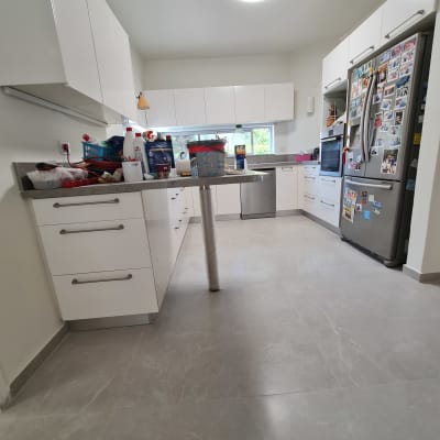 מטבח מודרני עם ארונות לבנים ומקרר מלא מגנטים