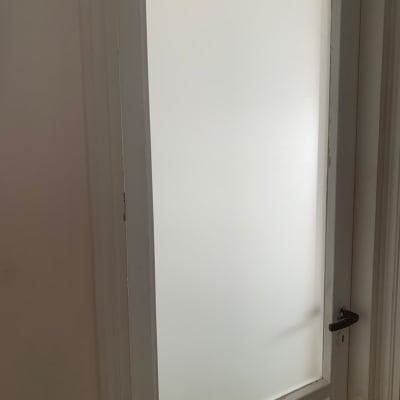 דלת זכוכית חלבית עם מסגרת לבנה וידית שחורה