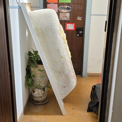 אמבטיה ישנה נשענת על קיר ליד דלת כניסה