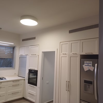 מטבח מודרני עם ארונות לבנים ותנור בנוי