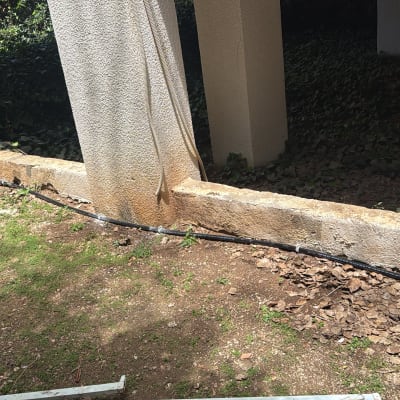 צינור מים מותקן לאורך קיר חיצוני בגינה