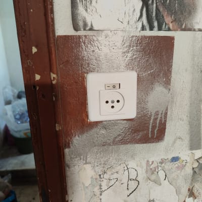 שקע חשמל עם מתג על קיר מתקלף