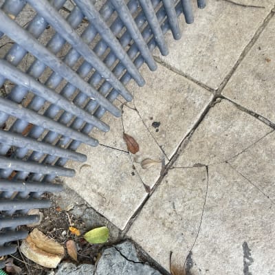 רצפת בטון סדוקה ליד גדר מתכת אפורה