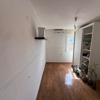 חדר עם רצפת עץ, ארון ומזגן על הקיר