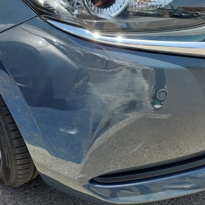 פנס קדמי של רכב עם שריטות על הפגוש