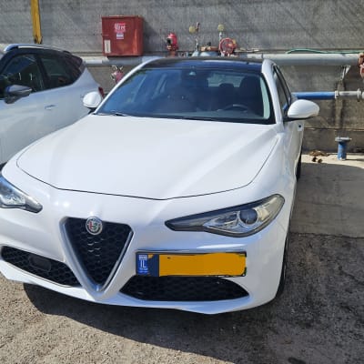 רכב לבן חונה ליד צינורות ומכונית נוספת