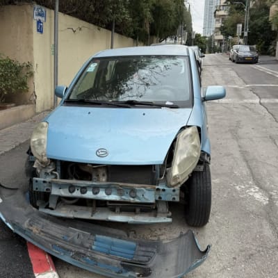 רכב כחול עם פגוש קדמי פגום ברחוב עירוני